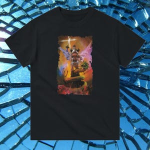 May include: Black t-shirt with a colorful graphic print of a figure with wings standing on a snake. The figure is holding a sword and has a crown on its head.
