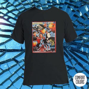 Op de afbeelding: Zwart T-shirt met een kleurrijke grafische print van een band genaamd "Gleaming the Cube". De afbeelding toont een groep mensen in een cartoon-stijl, met een rood, geel en blauw kleurenschema. De tekst "Gleaming the Cube" is in witte letters met een zwarte omtrek.