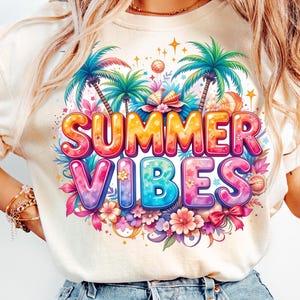 Op de afbeelding: Cr&egrave;mekleurig T-shirt met een levendige afbeelding met de tekst "SUMMER VIBES". Het ontwerp bevat kleurrijke bubbelletters, palmbomen, bloemen en strandthema-elementen. De algehele esthetiek is helder en vrolijk, perfect voor de zomer.