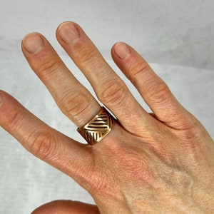 Peut inclure: Une bague large en cuivre avec un motif géométrique gravé sur la surface.
