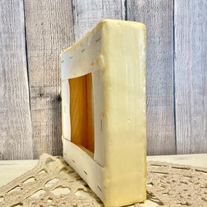 May include: A close-up of the side of a stretched canvas, showing the wooden frame and the white canvas stretched around it. The canvas is secured with staples.