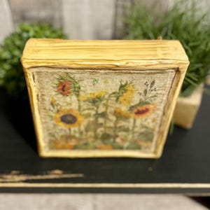 Framed vintage sunflower canvas art with beeswax textured finish, featuring rustic yellow sunflowers and wildflowers in farmhouse style canvas frame.