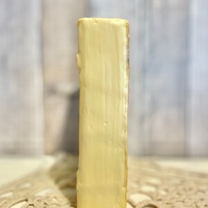 May include: A small, rectangular, cream-colored ceramic bookend with a smooth, slightly textured surface.