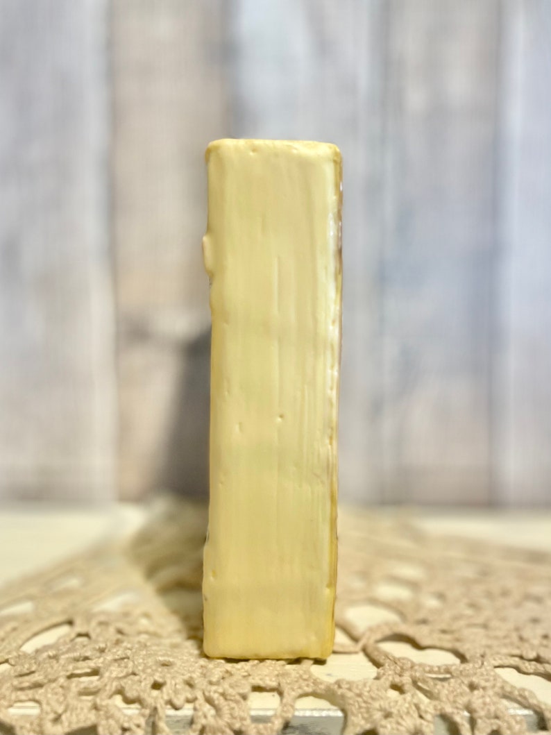 May include: A small, rectangular, cream-colored ceramic bookend with a smooth, slightly textured surface.
