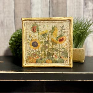 Framed vintage sunflower canvas art with beeswax textured finish, featuring rustic yellow sunflowers and wildflowers in farmhouse style canvas frame.