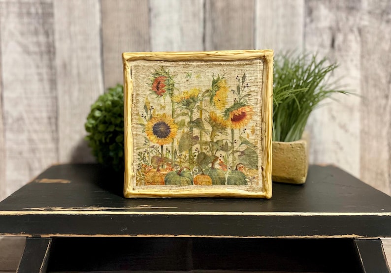 Framed vintage sunflower canvas art with beeswax textured finish, featuring rustic yellow sunflowers and wildflowers in farmhouse style canvas frame.