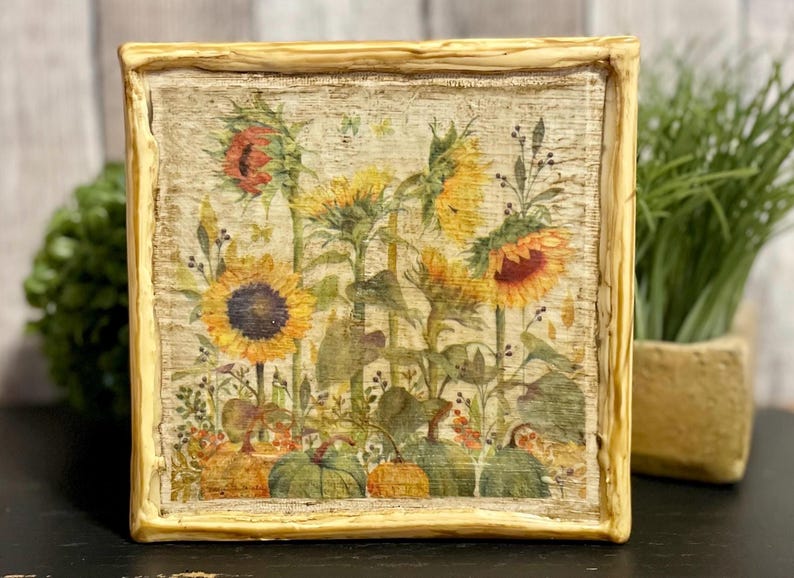 Framed vintage sunflower canvas art with beeswax textured finish, featuring rustic yellow sunflowers and wildflowers in farmhouse style canvas frame.