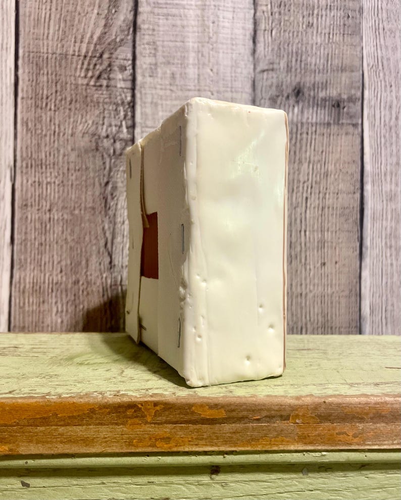 May include: A white box with a brown rectangle on the front. The box is sitting on a green surface.