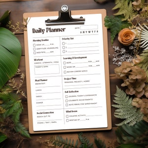May include: A black and white daily planner with sections for morning routine, workout, meal planner, learning and development, project time, self-reflection, social connection, and wind down. The planner has checkboxes and lines for writing.