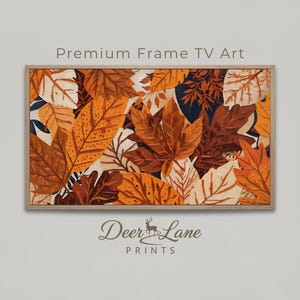 Może przedstawiać: Oprawione dzieło sztuki przedstawiające kolaż jesiennych liści w odcieniach pomarańczu, brązu i kremu. Dzieło sztuki jest oznaczone jako "Premium Frame TV Art" i "Deer Lane PRINTS". Liście są szczegółowe i warstwowe.