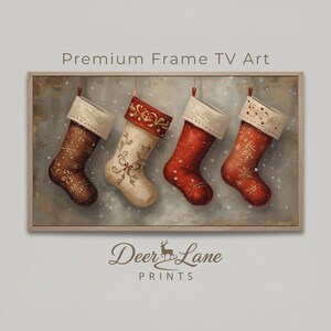 May include: A framed print featuring four Christmas stockings in a row. The stockings are red, cream, and brown, with decorative patterns and white cuffs. The text "Premium Frame TV Art" is at the top, and "Deer Lane Prints" is at the bottom.