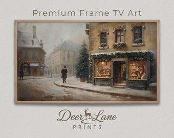 Pode incluir: Uma impressão emoldurada de uma cena de rua europeia com neve. A obra de arte apresenta uma loja decorada para o Natal, uma pessoa andando na rua e o texto "Premium Frame TV Art" e "Deer Lane PRINTS". A paleta de cores é suave, com tons de castanho, cinza e branco.