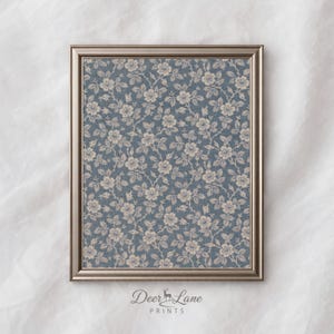 Puede incluir: Impresión enmarcada con un diseño floral azul y flores y hojas color crema. La impresión está en un marco plateado. El texto "Deer Lane Prints" está en la parte inferior de la impresión.