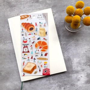 May include: A sheet of stickers featuring illustrations of various bakery items, including bread, croissants, and pastries. The stickers are on a white background with the text "ひっそり おやつ  sticker" in Japanese.
