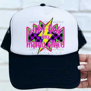 Op de afbeelding: Een witte en zwarte trucker-pet met een gele bliksem en de tekst "Only Hell My Mama Raised" in roze en paarse letters.