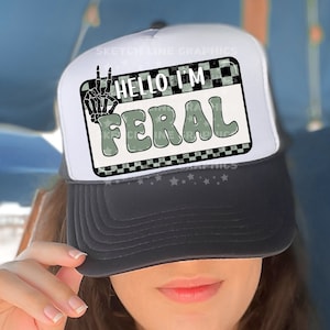 May include: A white and black trucker hat with a checkered pattern and a green and white patch that says "Hello I'm Feral".