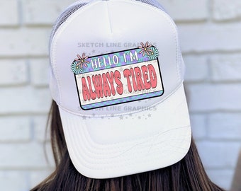 Pode incluir: Boné de caminhoneiro branco com um gráfico colorido que diz "Hello I'm Always Tired".
