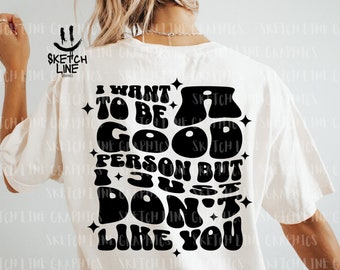 May include: White t-shirt with a black graphic print that reads "I want to be a good person but I just don't like you". The text is in a retro, bubble-like font.