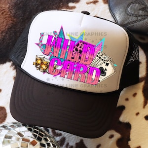 Puede incluir: Una gorra de camionero blanca y negra con un diseño "Wild Card" rosa y azul. El diseño incluye cartas de juego, una herradura y un par de gafas.