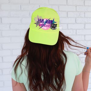 May include: A neon yellow baseball cap with a black and white tiger graphic and the text "Blue Collar Princess" in colorful letters.