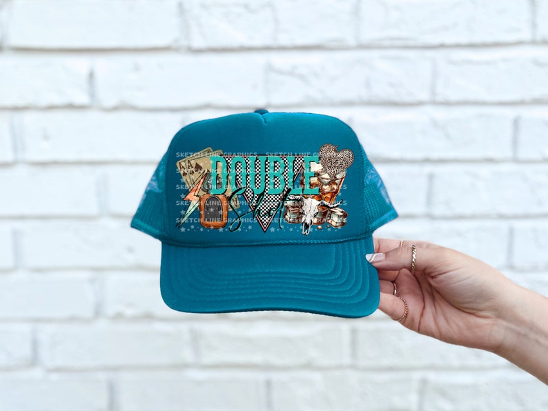 May include: Teal blue trucker hat with a mesh back. The front of the hat features a colorful graphic with the text "DOUBLE DOWN" and playing cards, dice, and a lightning bolt.