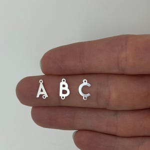 May include: Three silver letter charms, A, B, and C, with jump rings for attaching to jewelry.