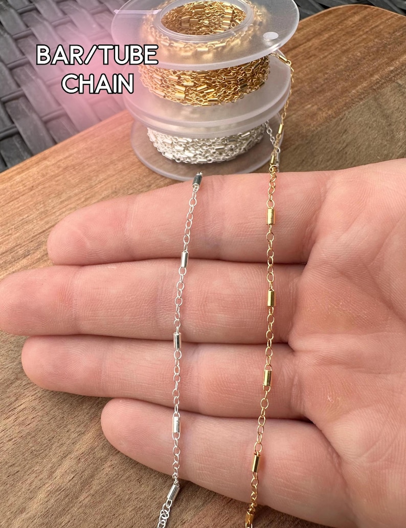 May include: Close-up of two bar/tube chains, one silver and one gold, displayed against a wooden surface. The chains are made of small, rectangular bars connected by delicate links. The text "BAR/TUBE CHAIN" is visible in the upper left corner.