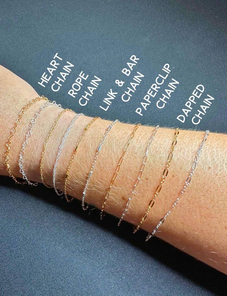 May include: A selection of delicate chain bracelets in gold and silver, displayed on a wrist. Styles include heart, rope, link & bar, paperclip, and dapped chains. Text labels identify each style. The background is a dark, solid color.