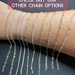 May include: A variety of gold, silver, and mixed metal chains are displayed on a person's wrist. The chains are all different styles, including heart, box, and cable chains. The text "CHECK OUT OUR OTHER CHAIN OPTIONS" is displayed above the chains.