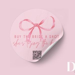 Könnte beinhalten: Runder rosa Aufkleber mit einer rosa Aquarell-Schleife und dem Text "BUY THE BRIDE A SHOT she's tying the knot" und einem QR-Code. Der Aufkleber hat eine abziehbare Ecke. Der Text "DESIGNED BY DK Shop on Etsy" befindet sich am unteren Rand des Aufklebers.