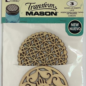 May include: Three wooden round mason jar lid inserts with intricate cut-out designs. The designs are a floral pattern, a geometric pattern, and a simple circle pattern. The package says "Transform Mason" and "New Nuevo".