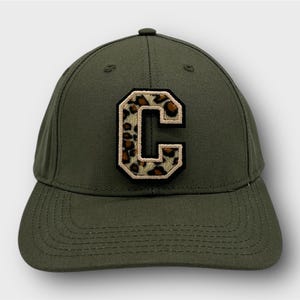Könnte beinhalten: Eine grüne Baseballkappe mit einem leopardengepunkteten Buchstaben "C"-Patch auf der Vorderseite.