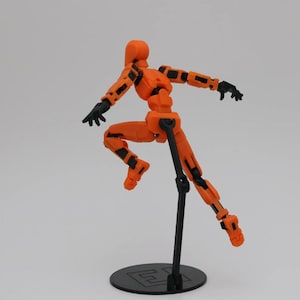 May include: Orange and black articulated action figure with a poseable body, standing on a black display stand.
