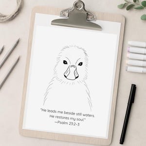 May include: A black and white line drawing of a duckling on a white paper, clipped to a wooden clipboard. The drawing is accompanied by the text "He leads me beside still waters. He restores my soul." -Psalm 23:2-3. A black pen is on the right.