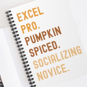 May include: A white spiral notebook with the text "EXCEL PRO. PUMPKIN SPICED. SOCIALIZING NOVICE." printed in orange and brown.