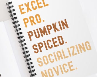Könnte beinhalten: Ein weißes Spiralnotizbuch mit dem Text "EXCEL PRO. PUMPKIN SPICED. SOCIALIZING NOVICE." in orange und braun gedruckt.
