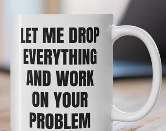 May include: White ceramic coffee mug with black text that reads "Let me drop everything and work on your problem."