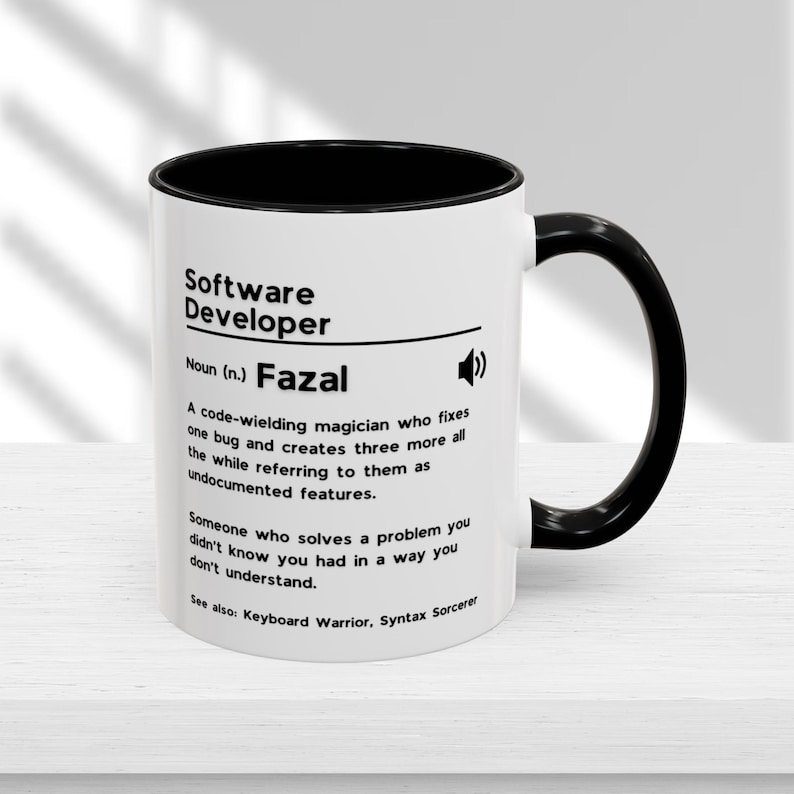 Pu&ograve; includere: Una tazza da caff&egrave; bianca con bordo e manico neri. La tazza presenta una grafica in bianco e nero che dice "Sviluppatore software" e definisce il termine come "Un mago che maneggia il codice che corregge un bug e ne crea altri tre, mentre li definisce come funzionalit&agrave; non documentate." La tazza dice anche "Nome (n.) Fazal" e "Vedi anche: Guerriero della tastiera, Stregone della sintassi".