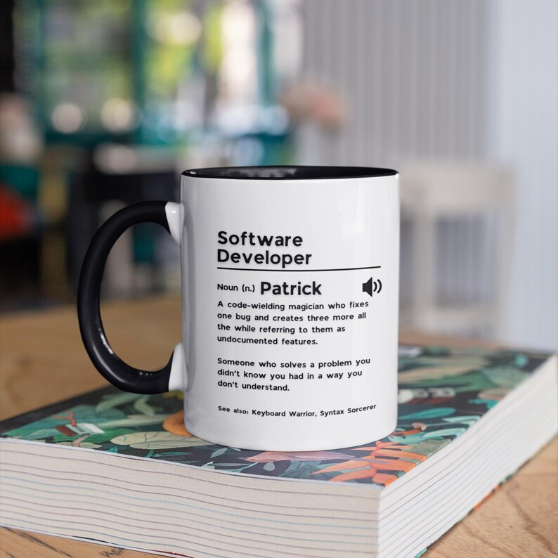 Pu&ograve; includere: Una tazza in ceramica bianca con manico e bordo neri. La tazza presenta una grafica in bianco e nero con il testo "Software Developer" e la definizione "Sostantivo (n.) Patrick Un mago del codice che risolve un bug e ne crea altri tre, mentre li definisce come funzionalit&agrave; non documentate. Qualcuno che risolve un problema che non sapevi di avere in un modo che non capisci. Vedi anche: Guerriero della tastiera. Stregone della sintassi"