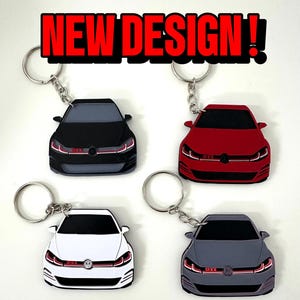 May include: Four car-shaped keyrings in black, red, white, and grey. Each keyring has a silver ring and the text "NEW DESIGN!" in a red and black banner above the keyrings. The cars have red accents.