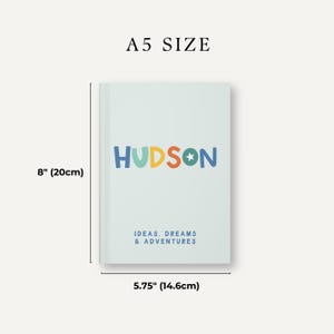 May include: A light blue notebook with the name "HUDSON" in colorful letters and the text "IDEAS, DREAMS & ADVENTURES" in blue. The notebook measures 8 inches by 5.75 inches.