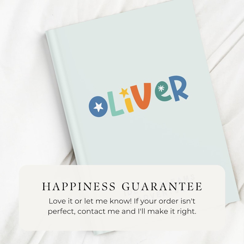 May include: A light blue notebook with the name "OLIVER" written in colorful letters. The notebook has a happiness guarantee message printed on the bottom.