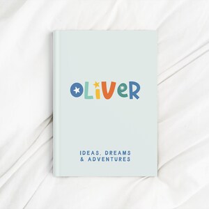 May include: A light blue notebook with the name "Oliver" in colorful letters and the text "Ideas, Dreams & Adventures".