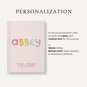Może przedstawiać: R&oacute;żowa okładka dziennika z imieniem "Abbey" w kolorowych literach z kwiatami. Tekst "IDEAS, DREAMS & ADVENTURES" znajduje się na dole okładki.