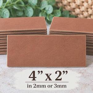 May include: A stack of rectangular brown leather tags with smooth surfaces and clean edges. The text on the image indicates the dimensions are 4 inches by 2 inches, with a thickness of either 2mm or 3mm for these leather labels.