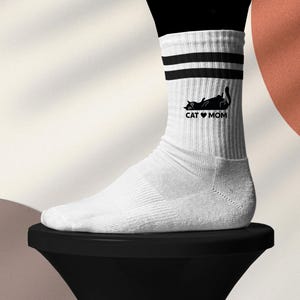 Könnte beinhalten: Weiße Socken mit schwarzen Streifen und einem schwarzen Katzenmotiv mit der Aufschrift "Cat Mom".
