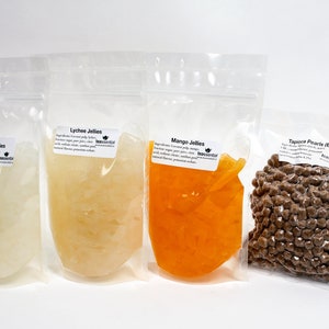 May include: Four clear plastic bags containing different types of jellies and tapioca pearls. The bags are labeled "Coconut Jellies", "Lychee Jellies", "Mango Jellies", and "Tapioca Pearls (Boba)".