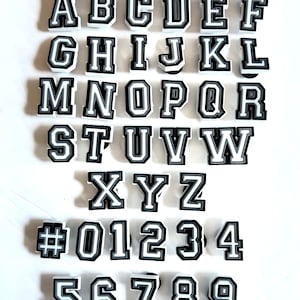 May include: Black and white alphabet and number letter stickers with a white background. The letters are in a varsity style font.