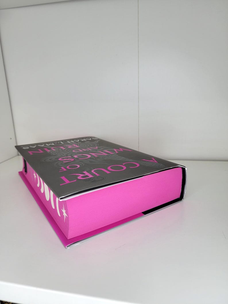 May include: A Court of Thorns and Roses book with a pink cover and a black and white illustration on the front.