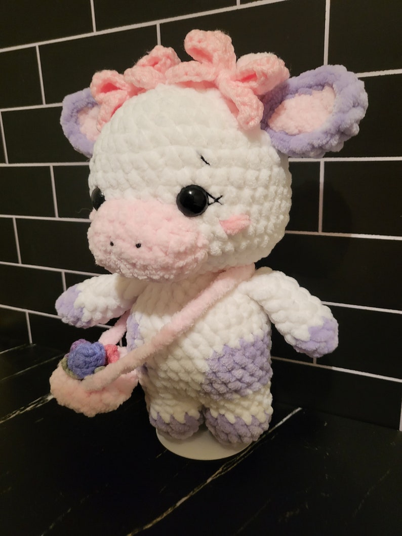Close-up of customizable crochet cow design from a PDF pattern, emphasizing the adorable head shape, ears, and optional floral accessories.
